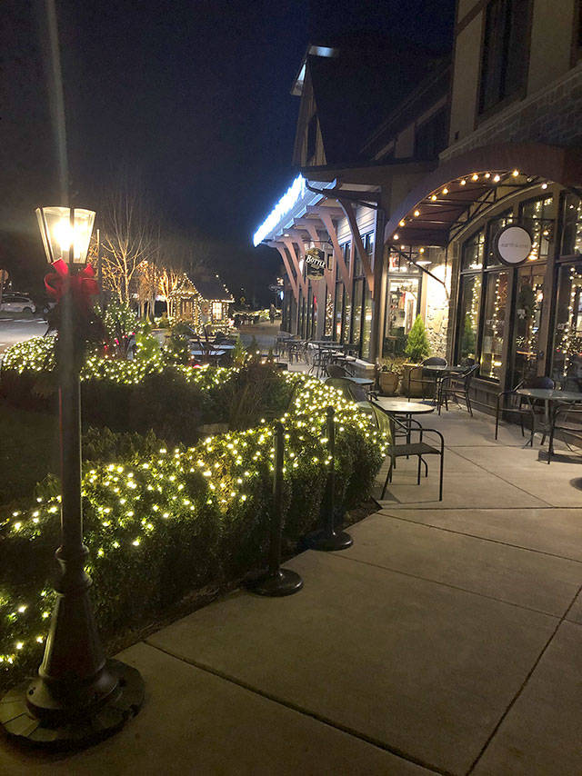 The sidewalks are lit up at night with decorations.