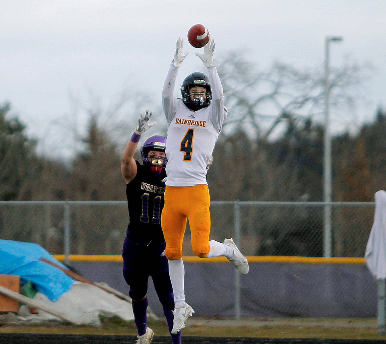 Bainbridge receiver Austin Coupland outleaps a Sequim defender for a reception. (Mark Krulish/Kitsap News Group)