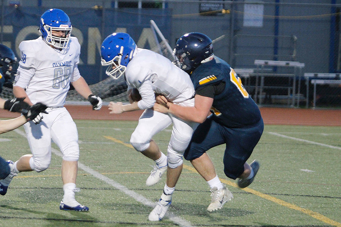 Bainbridge sophomore Sasha Herrmann brings down Olympic quarterback Dylan Boschee-Perry for a sack in his team’s 34-28 victory. (Mark Krulish/Kitsap News Group)