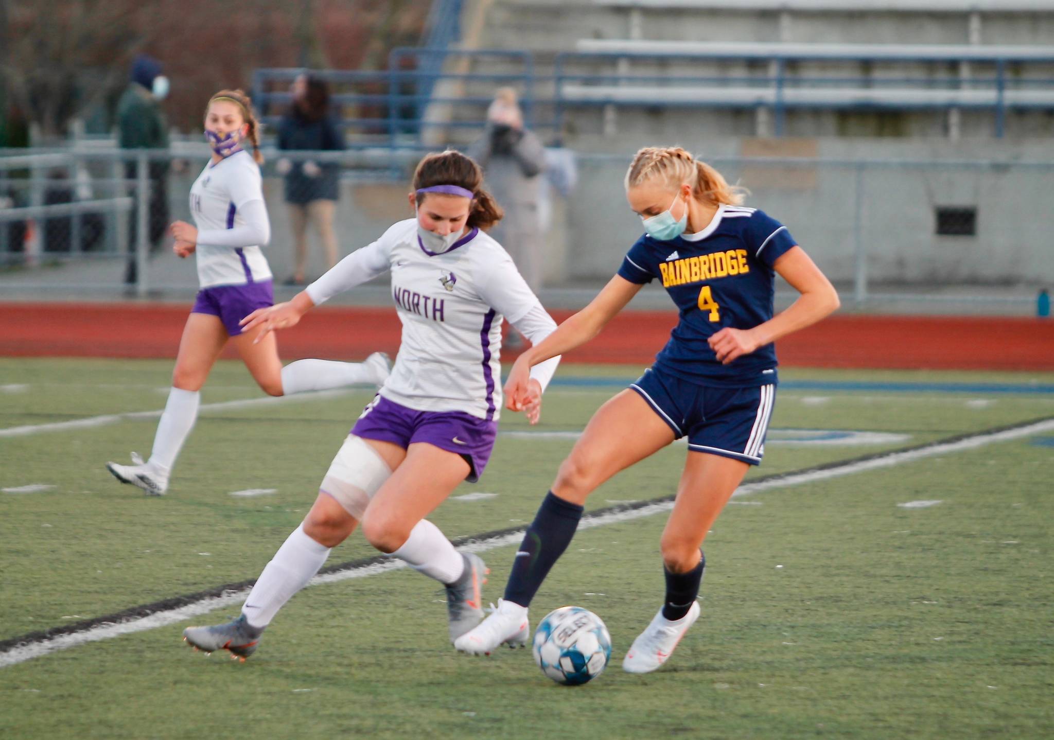 North Kitsap’s Sydnee Hogan and Bainbridge’s Chloe Boeker (4) spar for a loose ball. (Mark Krulish/Kitsap News Group)