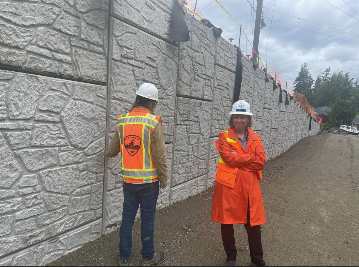 Dian Lenius, Poulsbo’s director of Engineering, inspects the walls that separate the road from the shared-use path on the roundabout project.