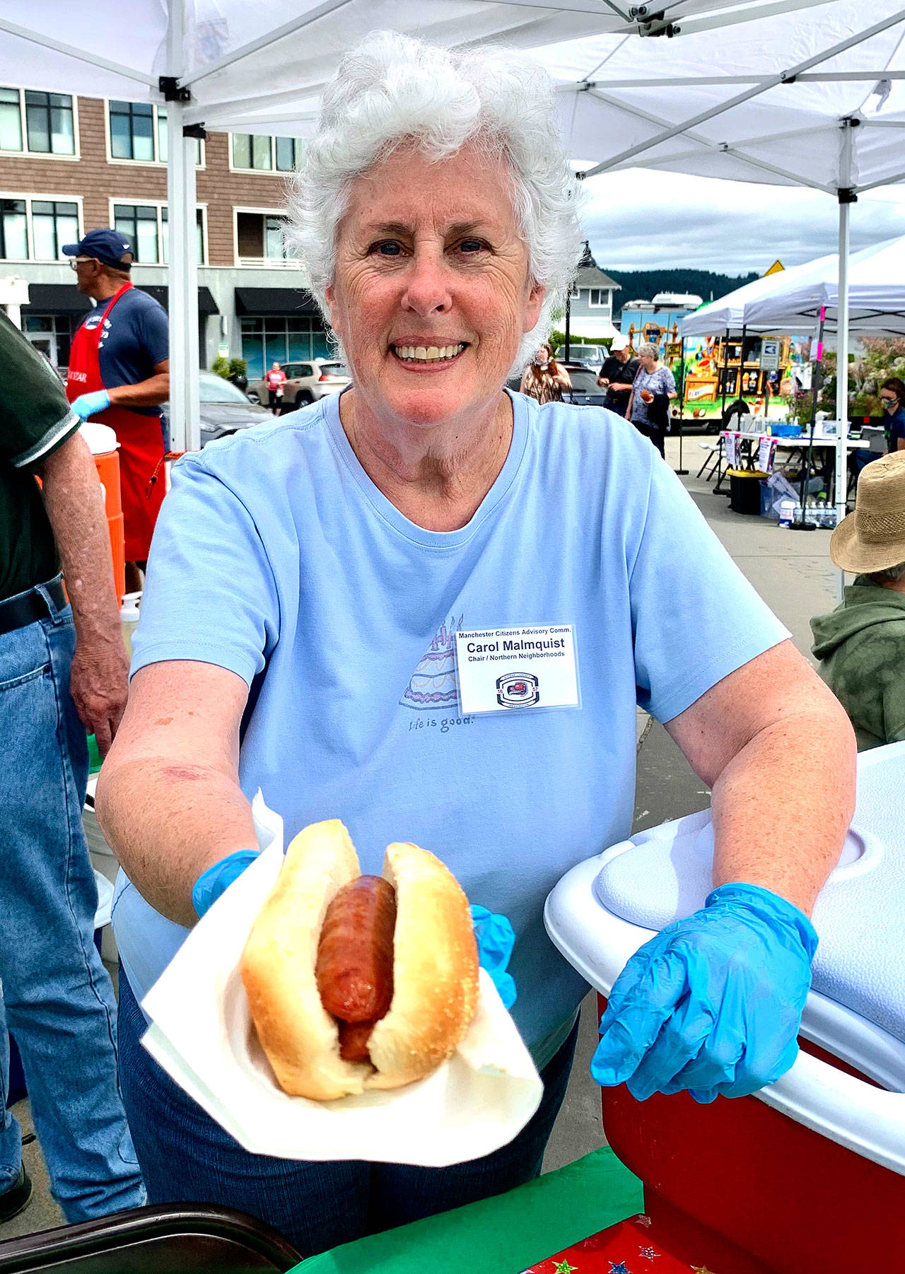 Volunteer Carol Malmquist offers a free hot dog to a visitor to the festival. (Bob Smith | Kitsap Daily News)