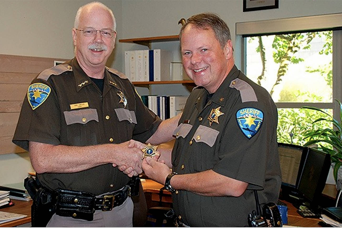 Now retired Kitsap County Sheriff Gary Simpson presents John Gese with a new sheriff’s badge following the announcement of Gese’s appointment as interim sheriff. Gese was appointed Kitsap County sheriff Monday by the Board of Commissioners. (File photo)