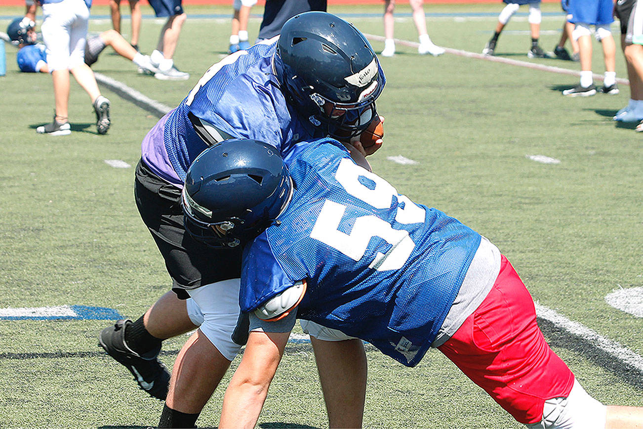 Strength up front: Wyatt Goade (59) and Axel Gibson go head-to-head in a drill during preseason practice. (Mark Krulish/Bainbridge Island Review)