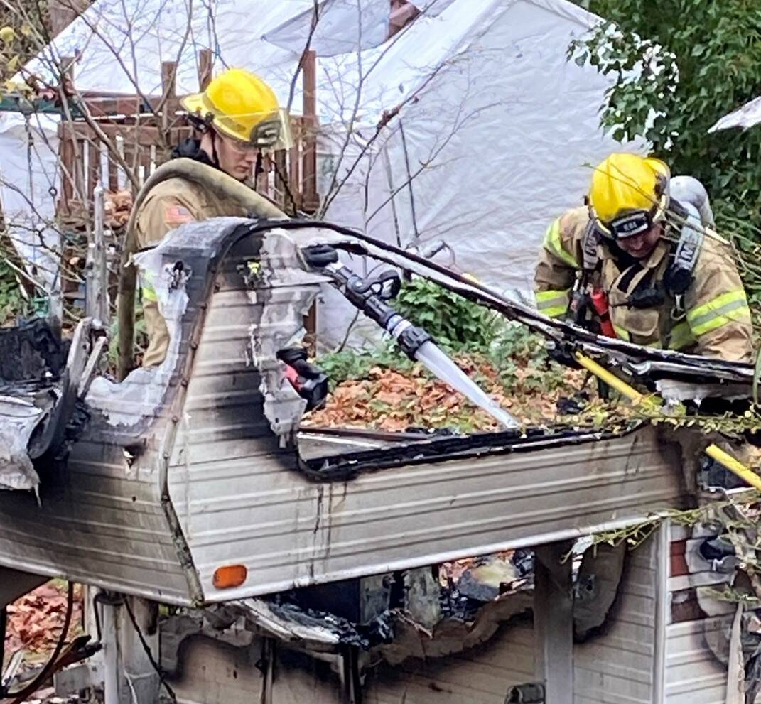 NKF&R firefighters Michael Foreman, left, and Harry Hause extinguish stubborn hot spots after a Tuesday afternoon trailer fire in Suquamish. Courtesy Photo