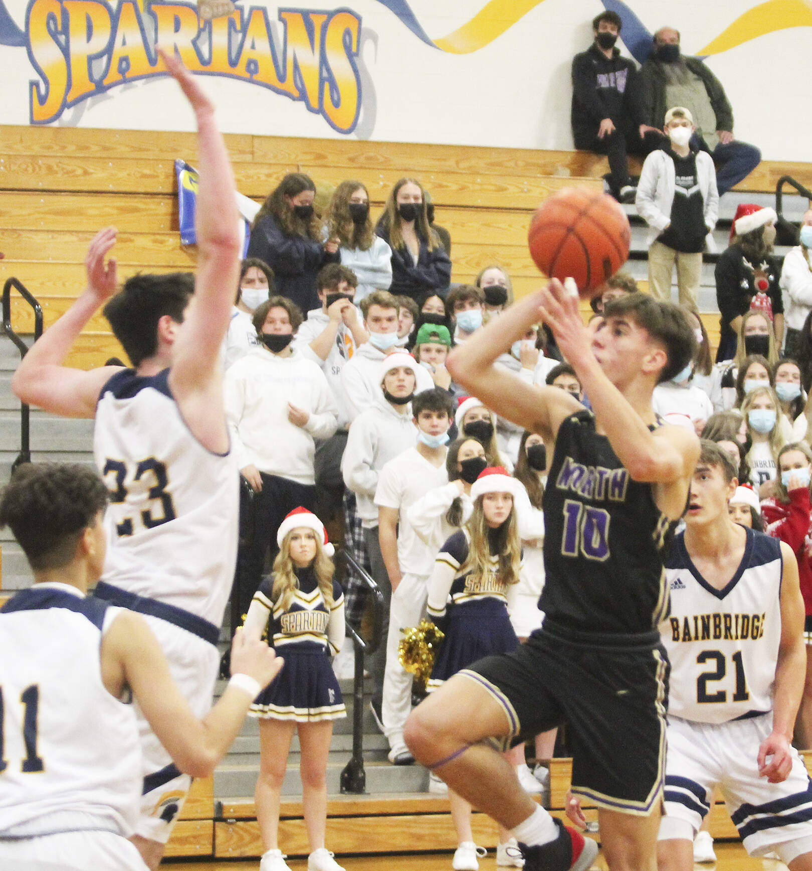 Cade Orness (10) drives to the hoop and puts up a short runner against James Carey (23) of Bainbridge. Breno Oguri (11) and Everett Moore (21) also defend. Steve Powell/North Kitsap Herald photos