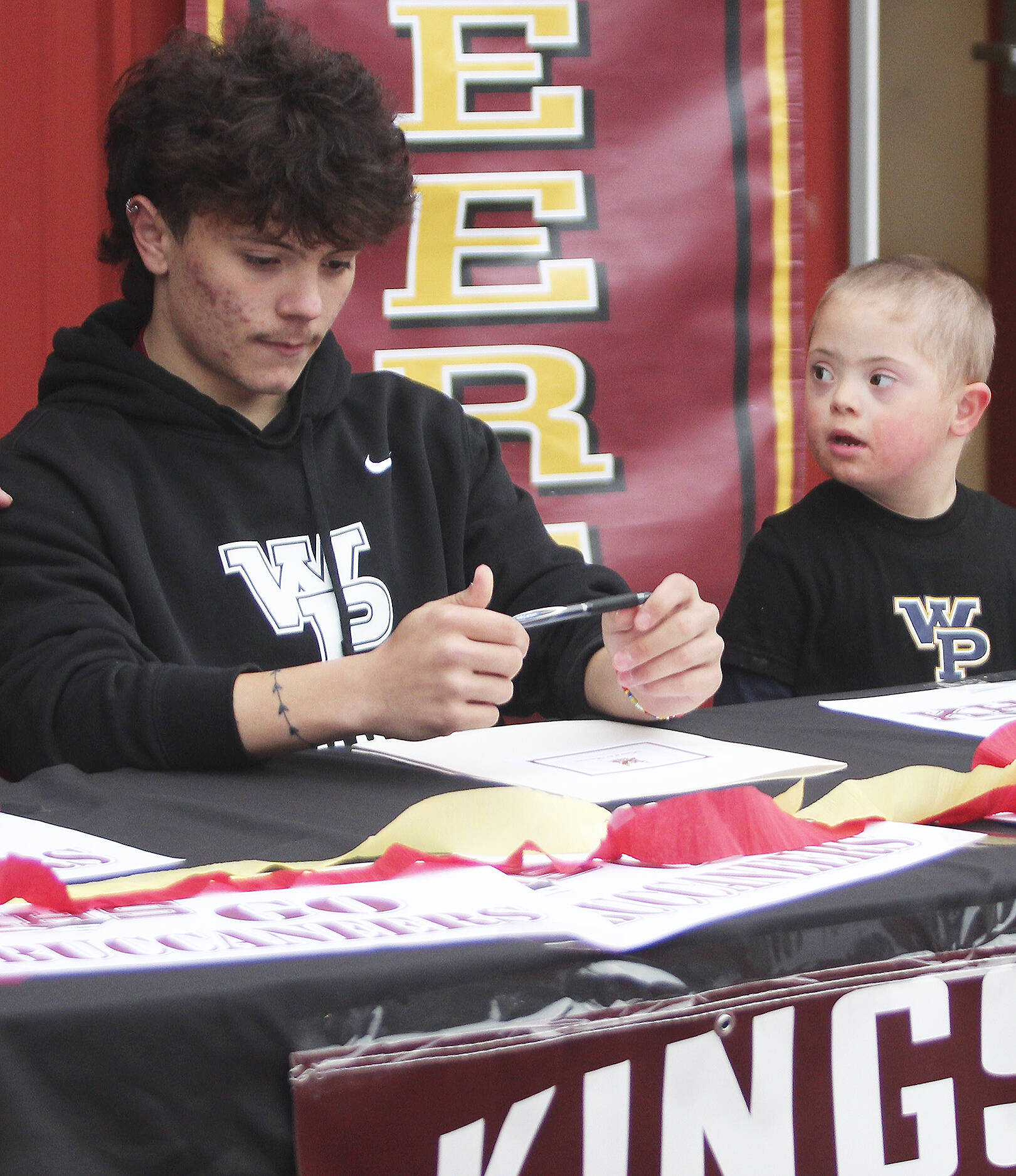 Kaden Schaefer of Kingston signs a letter of intent to play college soccer, while brother Zander, 5, looks on with admiration. Steve Powell/North Kitsap Herald photos