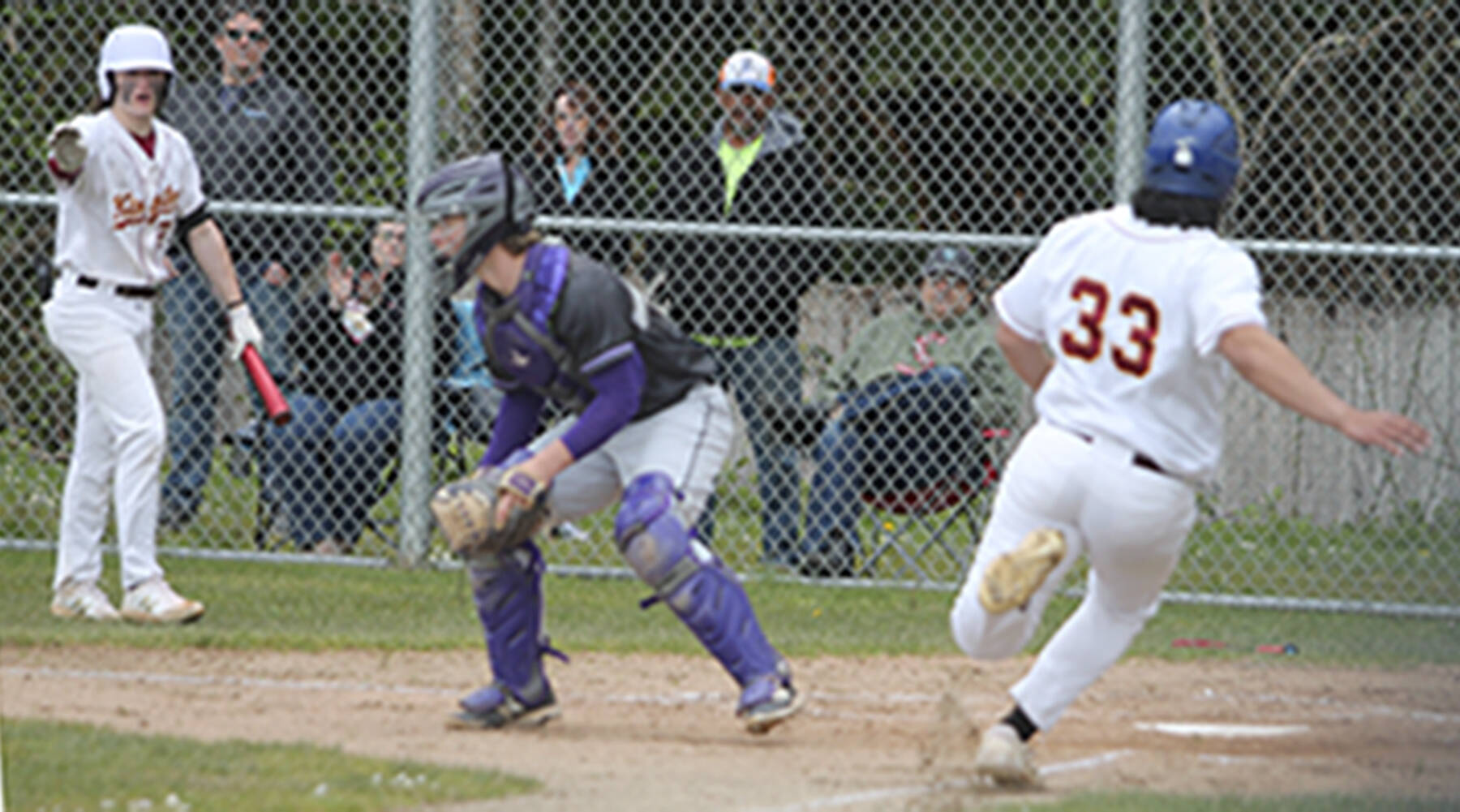 Kingston sophomore Peau Tameilau (33) slides safety into home plate as catcher Colton Bower of North Kitsap awaits the throw. Steve Powell/North Kitsap Herald photos