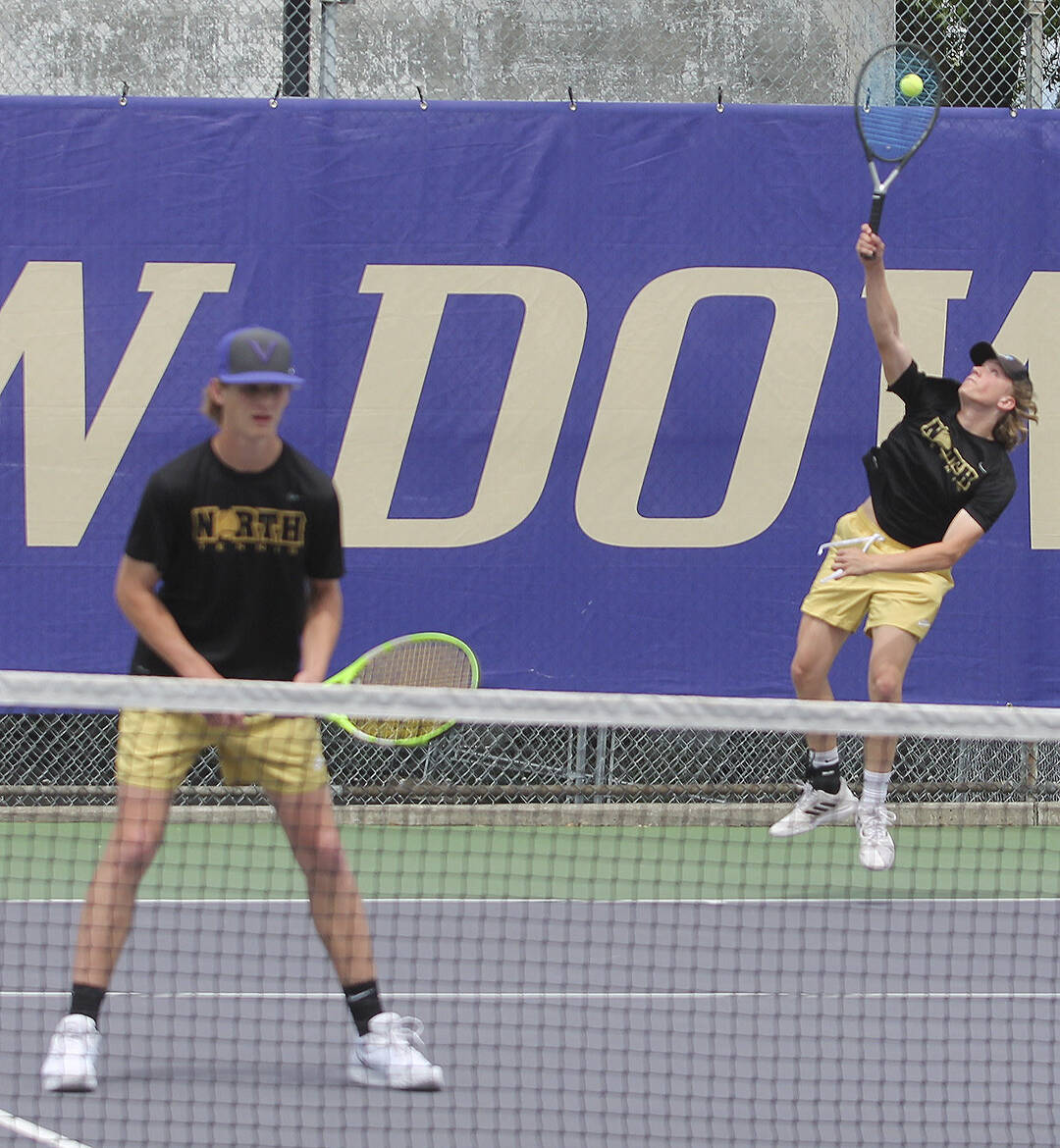 Ethan Gillespie serves while Carl Burchill plays the net in their state match.