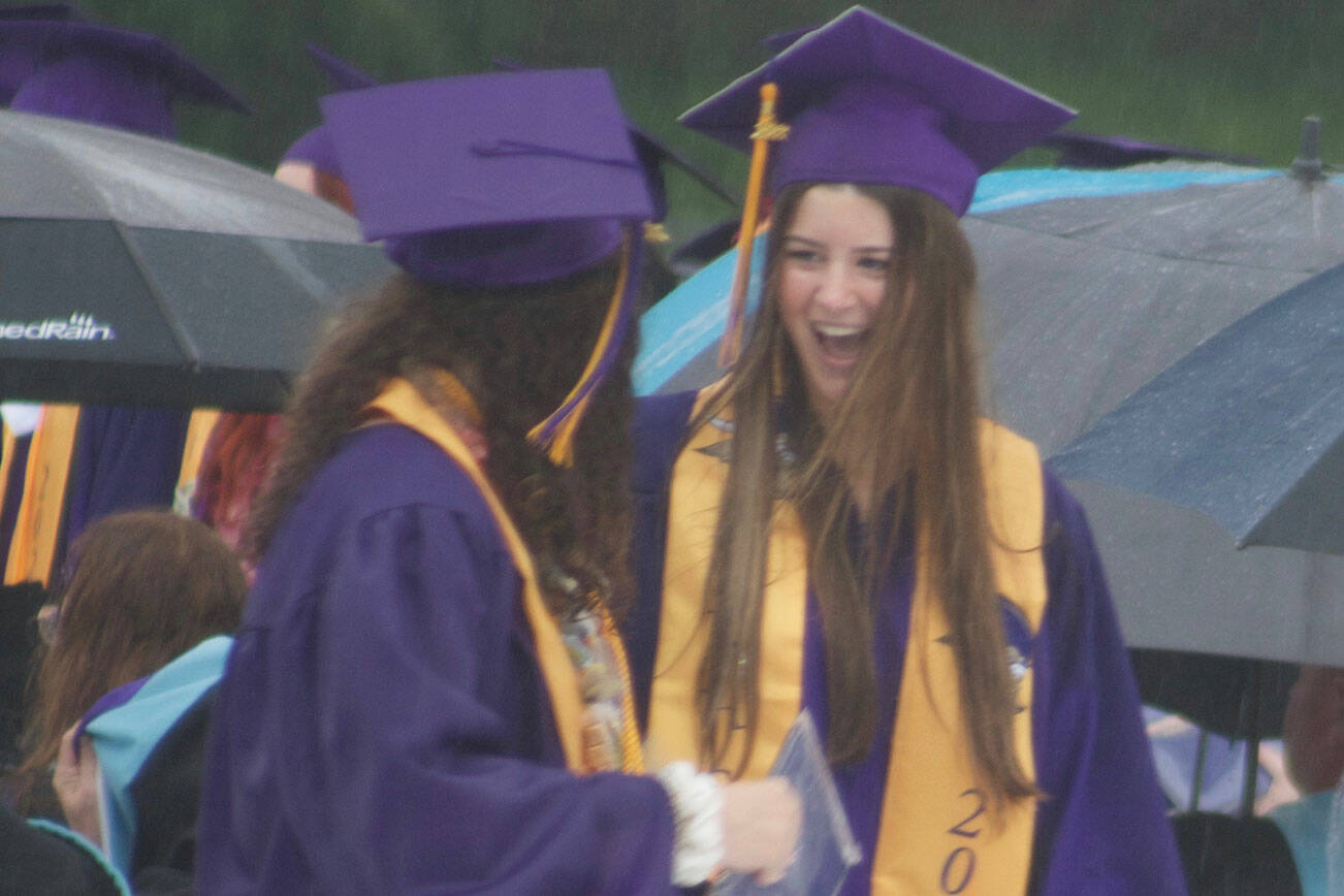 Two graduates celebrate after receiving their diplomas.