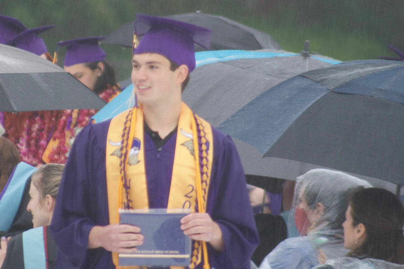 A graduate smiles toward the crowd after receiving his diploma.