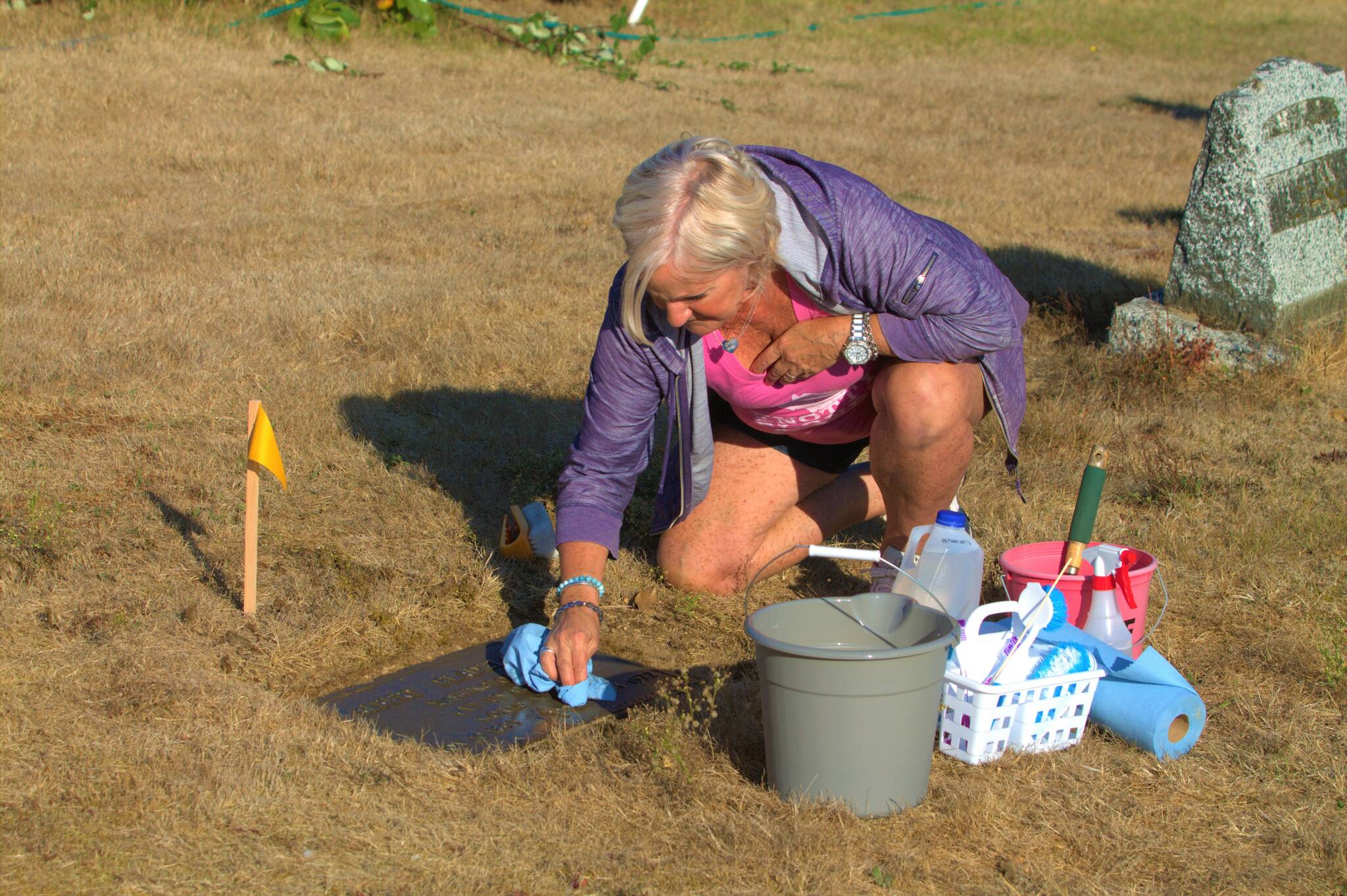 A volunteer works to clean the headstone of a World War 1 veteran. Elisha Meyer/Kitsap News Group Photos