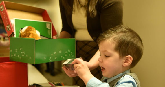 Rachel Garaard helps her son, Luke, 3, fill a box with items for Operation Christmas Child. Nancy Treder/Kitsap News Group Photos