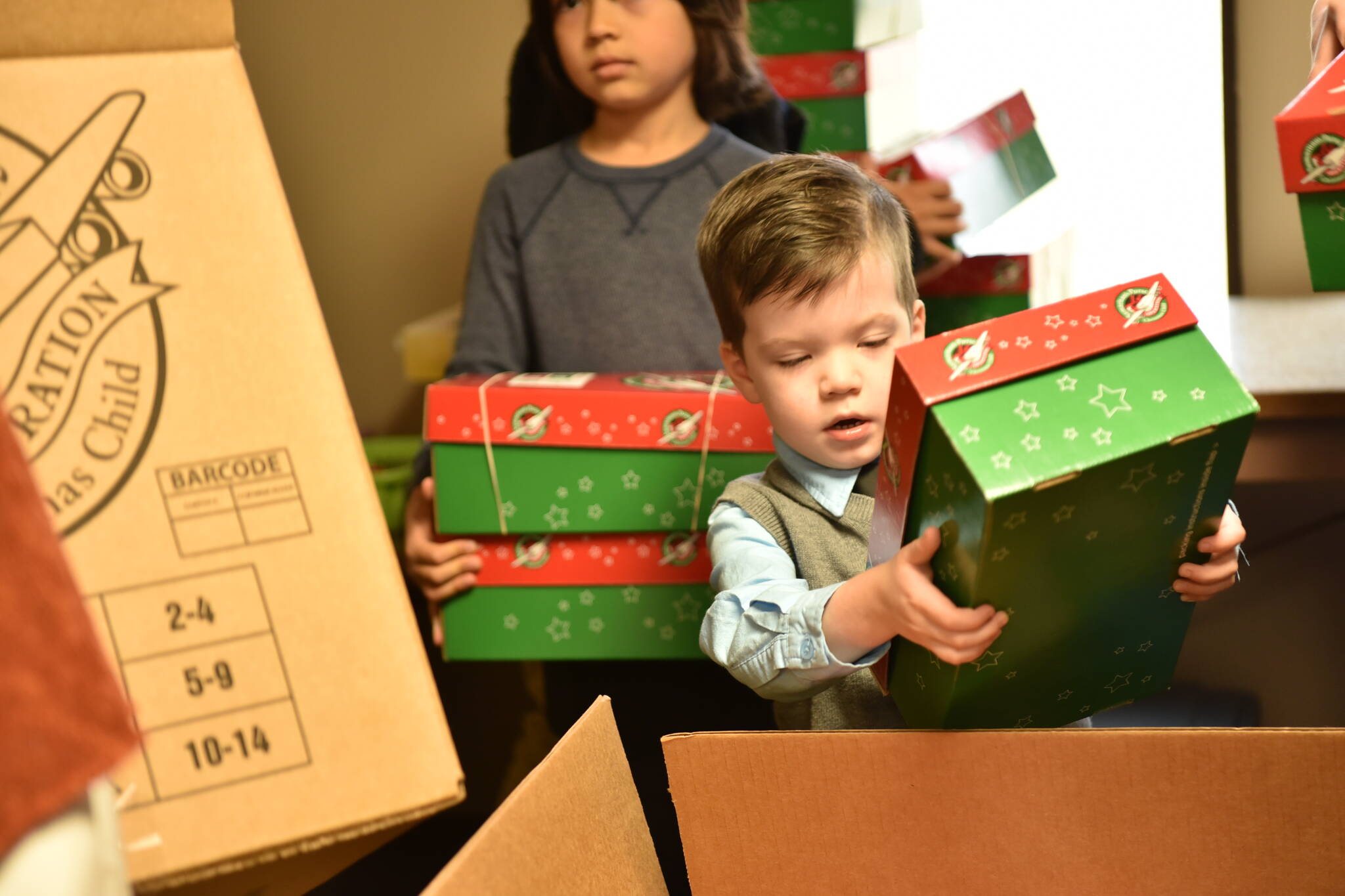 Luke Garaard, 3, puts a shoebox into the shipping box.