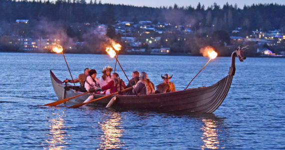 At dusk, the Poulsbo Sons of Norway Vikings escort the Lucia Bride by boat to shore at Waterfront Park in Poulsbo, where she lights the annual bonfire after the Viking King makes the Winter Solstice Proclamation. Nancy Treder/Kitsap News Group Photos