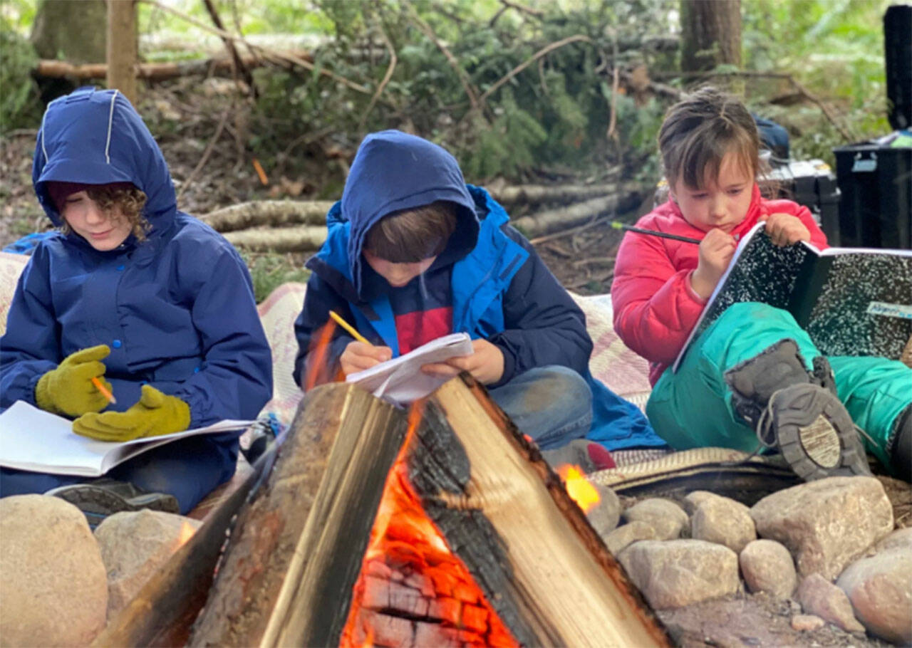 Students write in journals around a campfire at WildWise School. Courtesy Photos