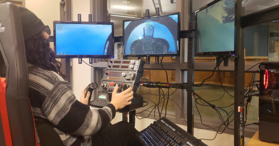 Kingston High School senior Kahn Kalii uses the flight simulator in the school library during lunch. It has a cockpit seat with all the controls and functions of a flying vessel. Tyler Shuey/Kitsap News Group Photos