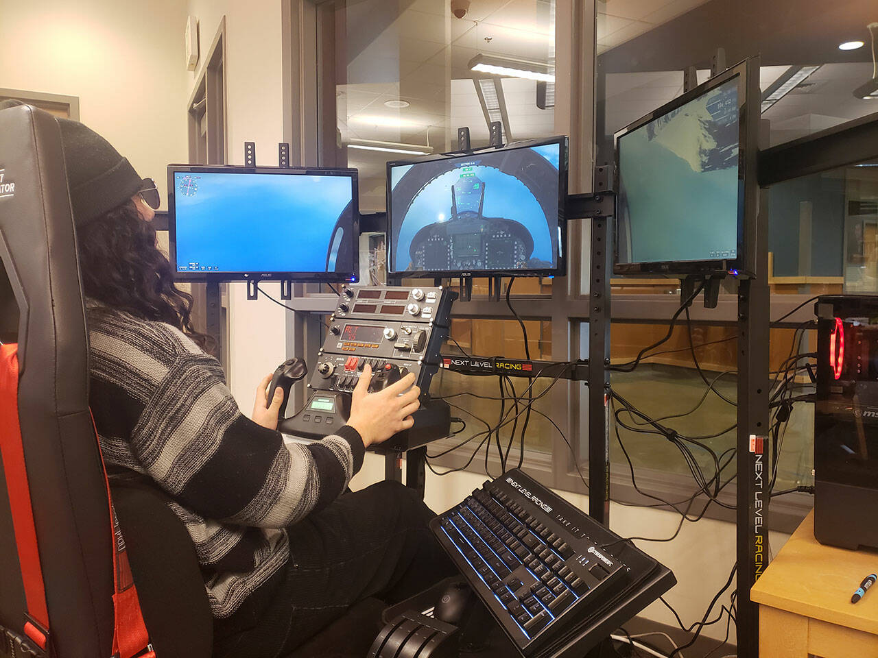 Kingston High School senior Kahn Kalii uses the flight simulator in the school library during lunch. It has a cockpit seat with all the controls and functions of a flying vessel. Tyler Shuey/Kitsap News Group Photos