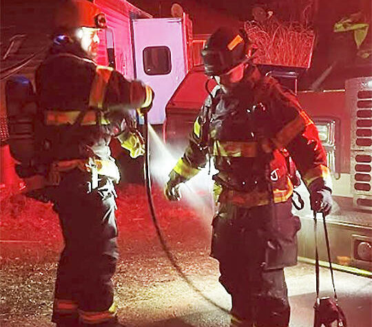 After making short work of a chimney fire NKF&R Lt. Scott Trueblood uses a hose to clean the gear worn by firefighter Tucker Burns. NKF&R Courtesy Photos
