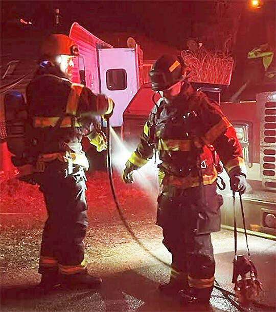 After making short work of a chimney fire NKF&R Lt. Scott Trueblood uses a hose to clean the gear worn by firefighter Tucker Burns. NKF&R Courtesy Photos