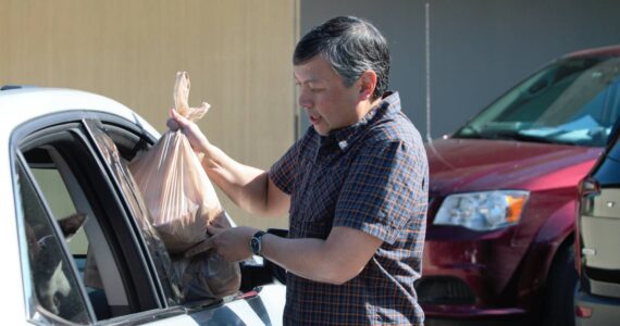 Sunnyslope Elementary counselor Roger Mangahas loads a meal for a veteran's family into the passenger side of the car. Elisha Meyer/Kitsap News Group Photos