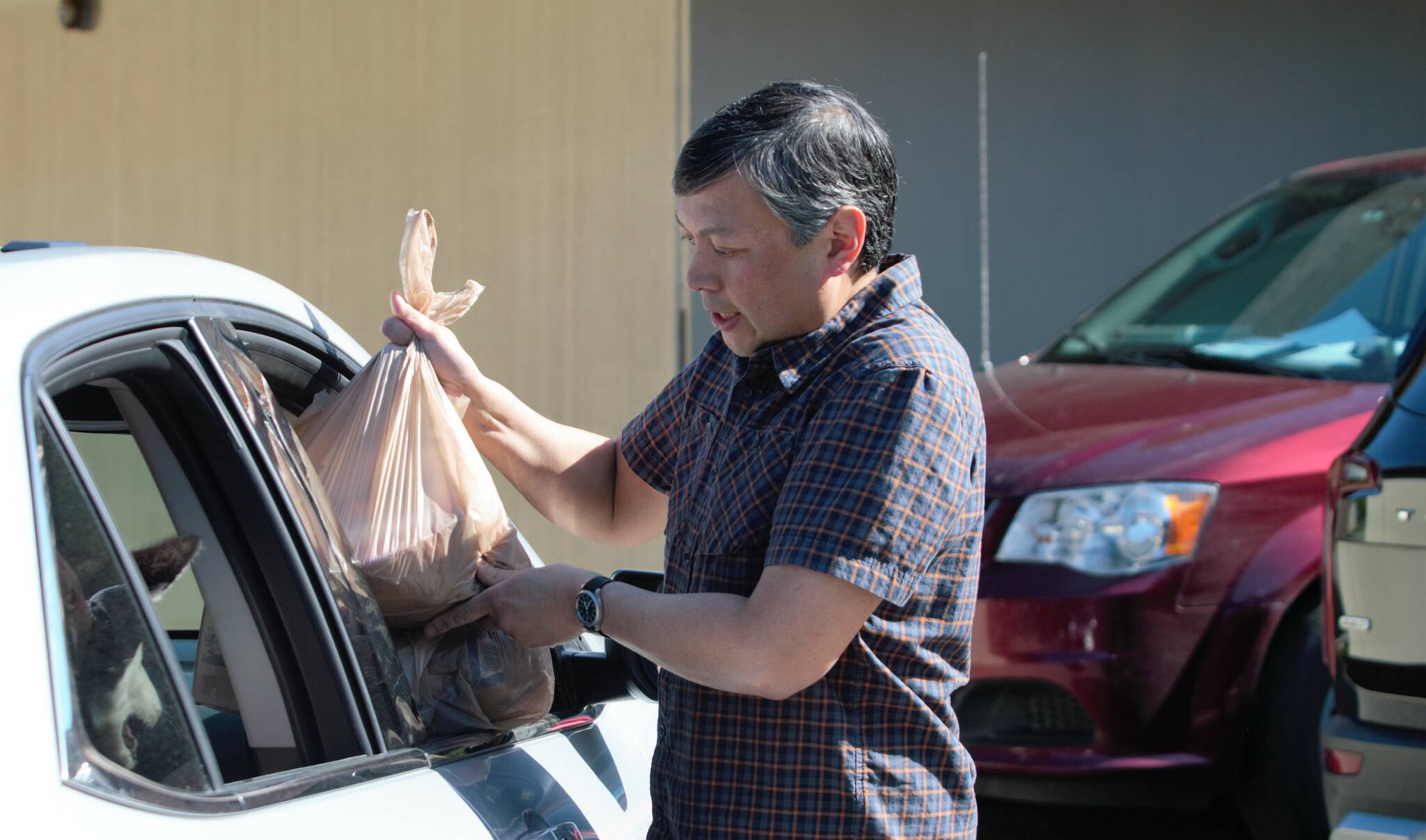 Sunnyslope Elementary counselor Roger Mangahas loads a meal for a veteran's family into the passenger side of the car. Elisha Meyer/Kitsap News Group Photos