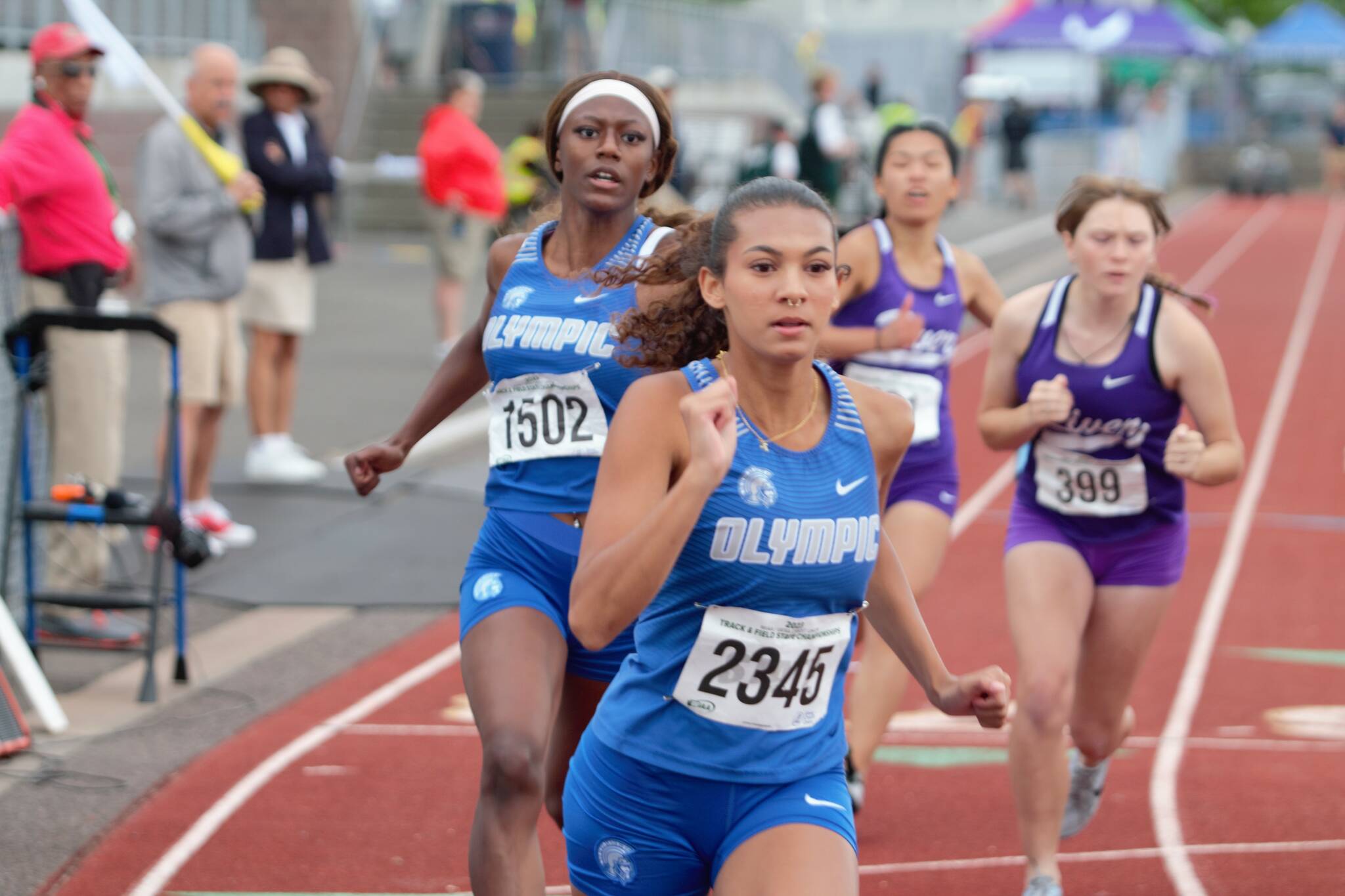 Elisha Meyer/Kitsap News Group 
Senior sprinter from Olympic High School N’Dya Hudson (back) approaches her senior teammate Aalliya Alcorn (front) for a baton handoff in the 4x200-meter relay.