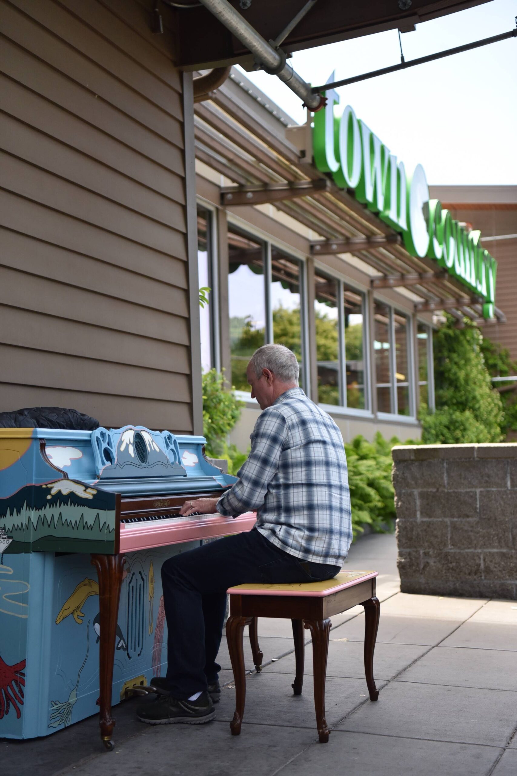 Del Hatch plays the piano in front of Town & Country.