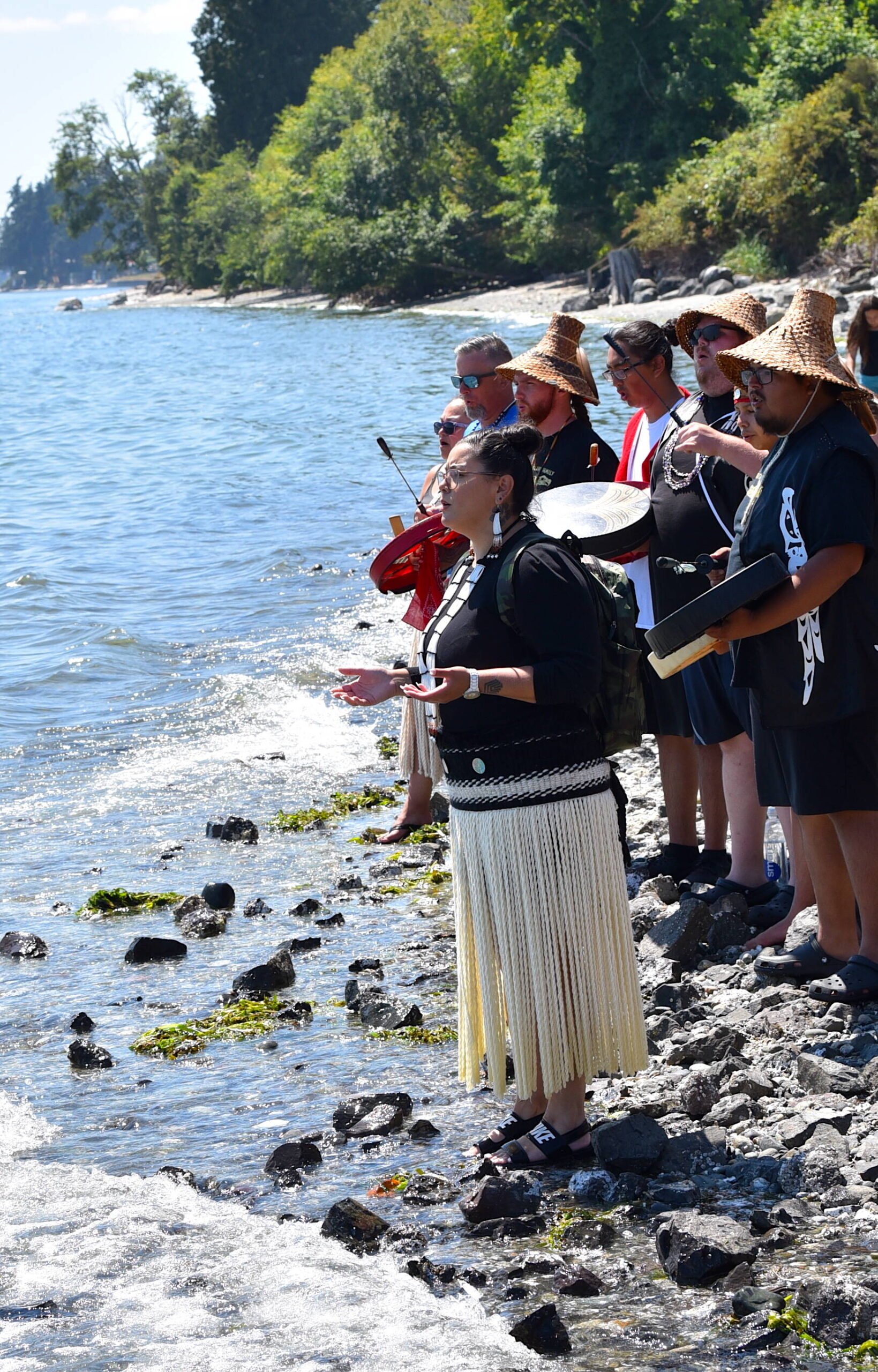 Suquamish tribal members greet canoes with song and drums July 28 on the beach in front of tribe's House of Awakened Culture.