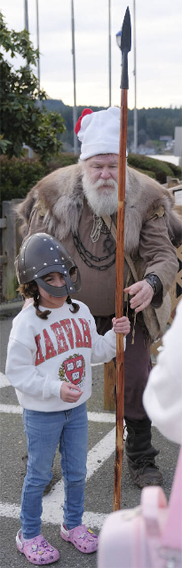 A Viking helps a young participant safely handle a spear during Viking Fest Feb. 10.
