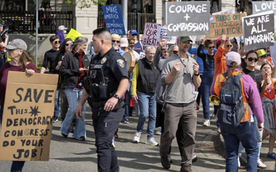 Marchers round the corner at Winslow Way and Madison Avenue, with police directing traffic.