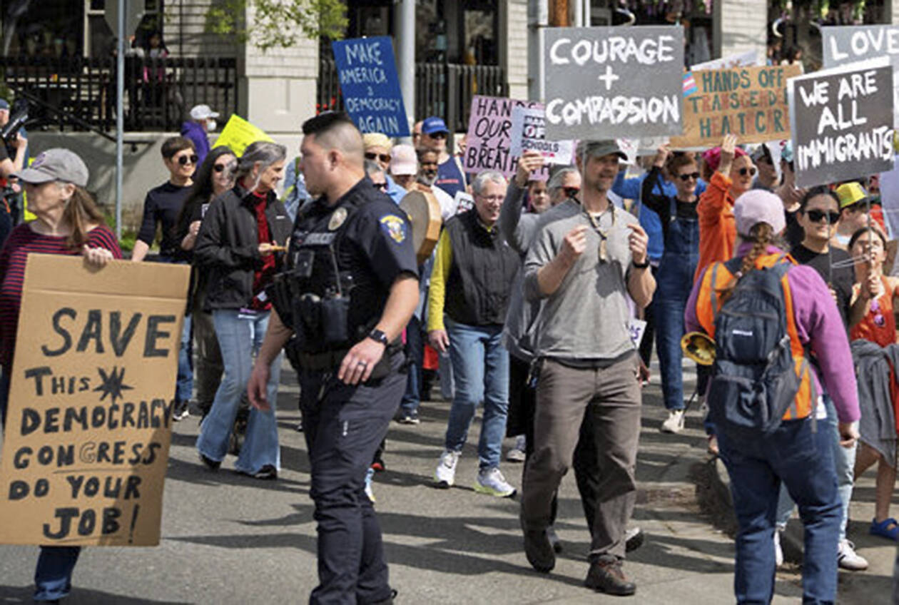 Marchers round the corner at Winslow Way and Madison Avenue, with police directing traffic.