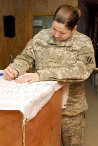 Pvt. Brandy Swackhammer signs a 3rd Infantry Division flag for Port Orchard resident Jason Overfield