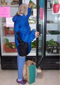 a woman helps herself to groceries at the fishline food bank.