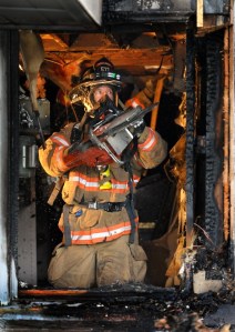Poulsbo firefighter/paramedic Andy Plenge cuts into the area damaged by fire looking for hotspots. Crews responded to the Virgina Point Road structure fire and found the basement of the unoccupied house in flames. The owner was out of state
