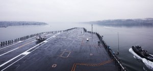 Sailors man the rails on USS John C. Stennis' (CVN 74) flight deck as the ship gets underway for a regularly scheduled deployment.