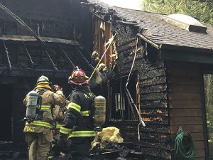 Firefighters check for hotspots on a house that was    heavily damaged by fire Nov. 30