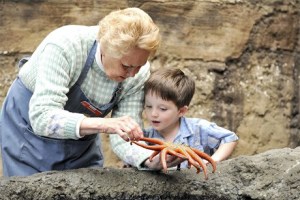 Marine Science Center volunteer Sharon Larsen shows off a starfish to visitor Justin Anderson.
