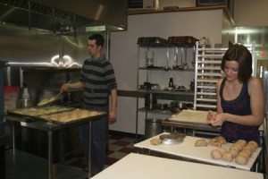 Brandyn Stone places a few bagels on a tray to cool after being boiled while Alyca Scott rolls dough at Evergreen Kitchen in Bremerton last week. Stonehouse Breads bakes in the co-op commercial kitchen and sells its New York-style bagels in stores and farmers markets around Kitsap County.