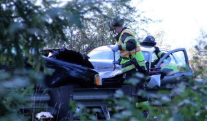 Firefighters work to untangle three cars from a collision on Highway 305.