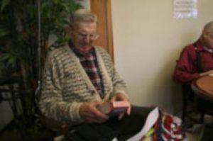 Paul Asher opens a Christmas present in the dining room at Bay Vista Commons during a Christmas lunch at the senior center. Seniors enjoy a special Christmas