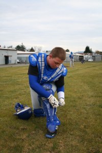 Bremerton High School baseball senior catcher Max Hayes straps up his gear during practice Tuesday. Hayes is one of four catchers in the Knights’ rotation and compares the position to a center in football