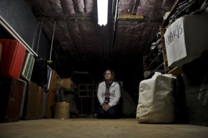 Costume and Props Director Jeanette Tucker kneels in the military room of the costume loft