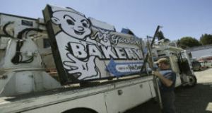 Brian Walters from Hanson Signs sets the safety bars in place to take the known McGavin Bakery sign back to his shop. The Bremerton bakery’s sign recently fell to the ground after a freelance painter was hired to paint the sign and accidently unhooked the safety cables.