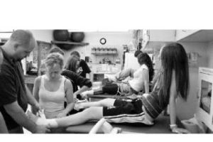 Head athletic trainer Chris Franklin demonstrates the proper ankle taping technique on student Nikki Taplin. The student trainers have been in the training room from 1-7 p.m since Aug. 18.