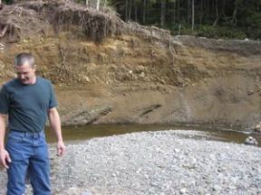 Bill Evalt stands in front of a portion of land on his property that was washed away during the December 2007 floods. At the top of the washout on the upper right is the road that Evalt has to drive to get to his property. The road is about 30 feet above Big Beef Creek.