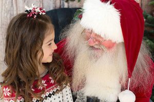 Santa Tim Carter reads to a little girl during a holiday event.                                Photo courtesy of Tim Carter