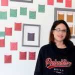 Victoria Ahlfors, outreach coordinator for Scarlet Road, stands in front of the donor appreciation wall at the new Scarlet Road location in downtown Bremerton. Michelle Beahm / Kitsap News Group