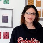 Victoria Ahlfors, outreach coordinator for Scarlet Road, stands in front of the donor appreciation wall at the new Scarlet Road location in downtown Bremerton. Michelle Beahm / Kitsap News Group