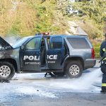 A South Kitsap Fire and Rescue firefighter cleans up after an engine fire that destroyed a Navy Region Northwest Police vehicle Dec. 14 in front of the Shell Food Mart at the intersection of Mile Hill Road and Woods Road. Firefighters sprayed water and foam to extinguish the fire. Bob Smith | Kitsap News Group